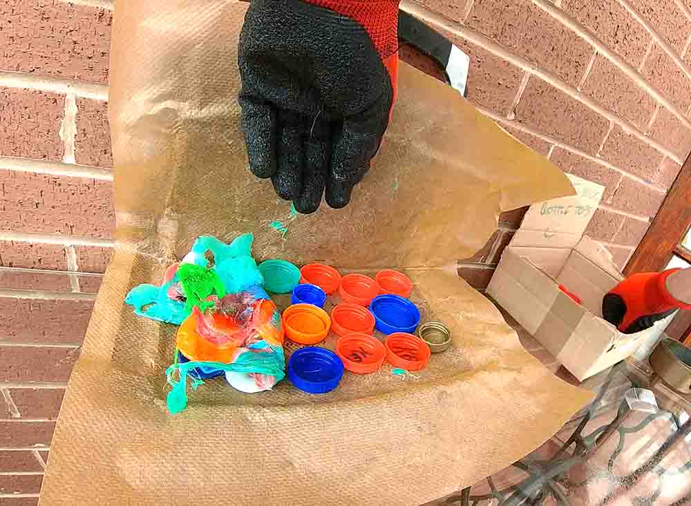 adding-more-bottle-tops-to-melted-plastic.jpg